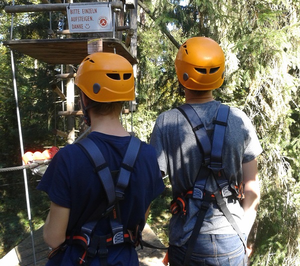 Zwei Personen mit Helm schauen auf den Kletterpark