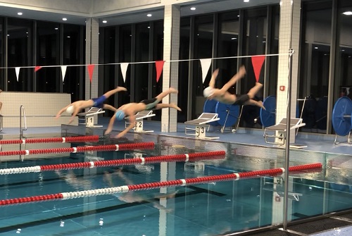 Drei Schwimmer beim Absprung