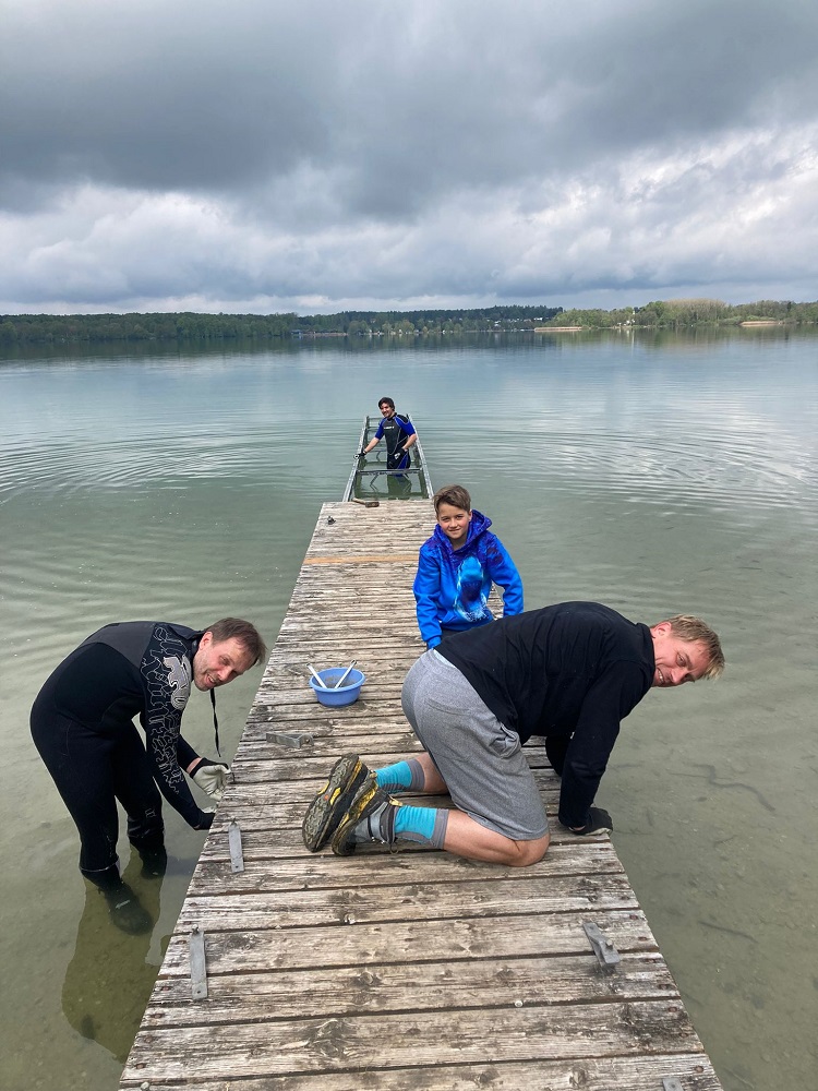 4 Personen bauen den Steg am See ein